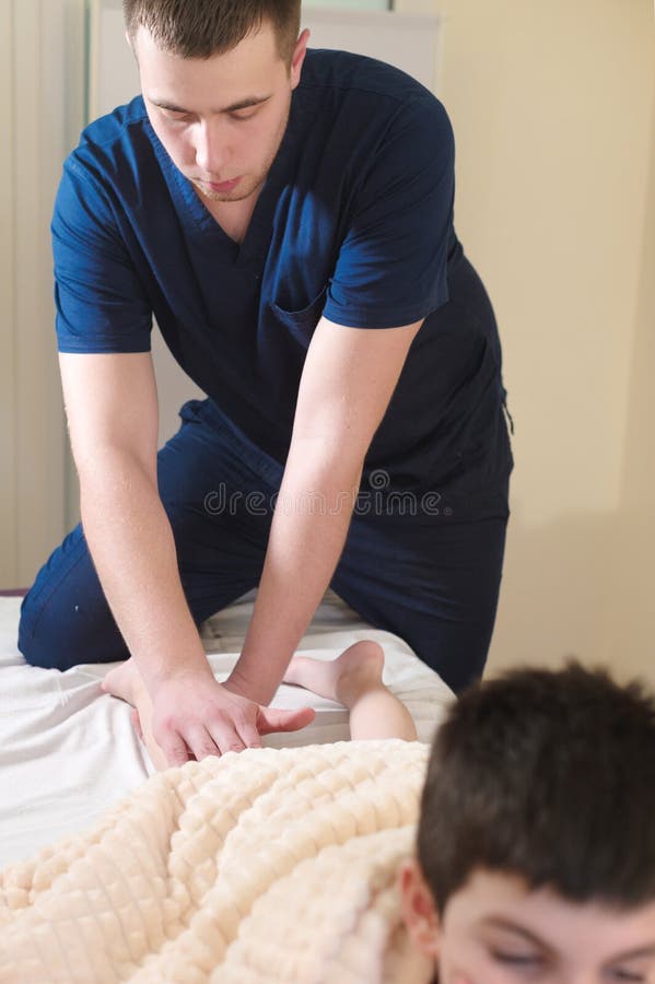 Primo piano delle mani maschii del chiropratico che massaggiano i vitelli di piccolo paziente Un ragazzino alla ricezione della p fotografie stock libere da diritti Primo piano delle mani maschii del chiropratico che massaggiano i vitelli di piccolo paziente Un ragazzino alla ricezione della p fotografie stock libere da diritti