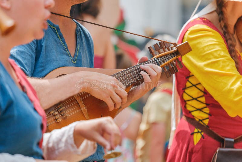 Primo piano delle parti del corpo e della chitarra medievali dei musicisti immagini stock Primo piano delle parti del corpo e della chitarra medievali dei musicisti immagini stock