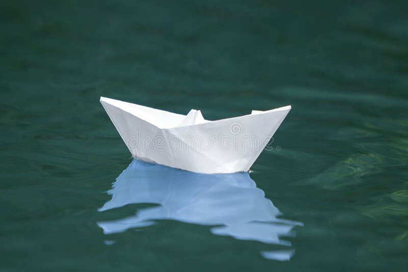 Primo piano delle quiete di galleggiamento della piccola barca di carta bianca semplice di origami immagini stock libere da diritti Primo piano delle quiete di galleggiamento della piccola barca di carta bianca semplice di origami immagini stock libere da diritti