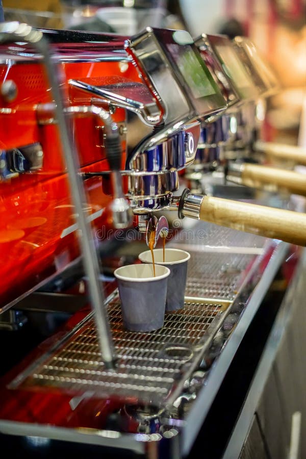 Primo piano di caffè espresso che versa dalla macchina rossa moderna del caffè fotografia stock Primo piano di caffè espresso che versa dalla macchina rossa moderna del caffè fotografia stock