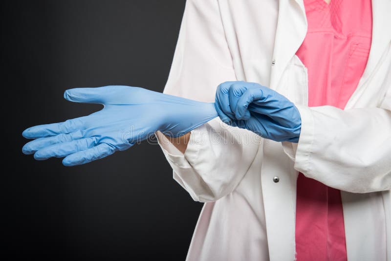 Primo piano di medico che indossa i suoi guanti sterili immagini stock Primo piano di medico che indossa i suoi guanti sterili immagini stock