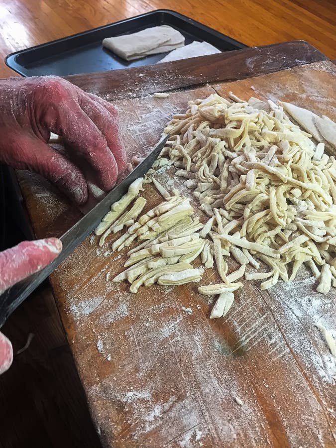 Primo piano di un coltello che taglia le tagliatelle casalinghe dell'uovo fotografia stock libera da diritti Primo piano di un coltello che taglia le tagliatelle casalinghe dell'uovo fotografia stock libera da diritti