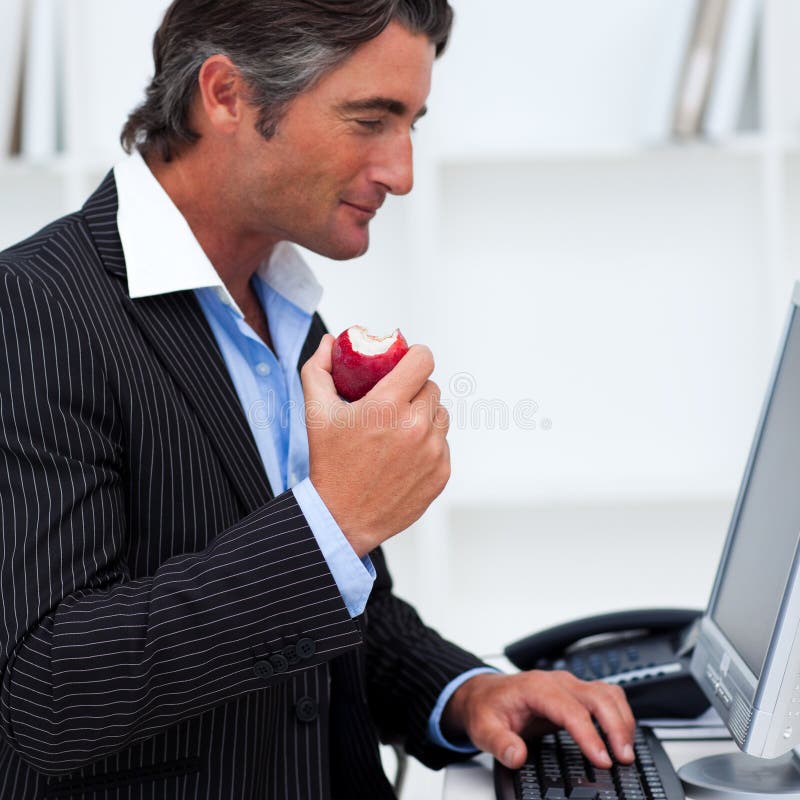 Primo piano di un uomo d'affari felice che mangia una mela rossa fotografia stock libera da diritti