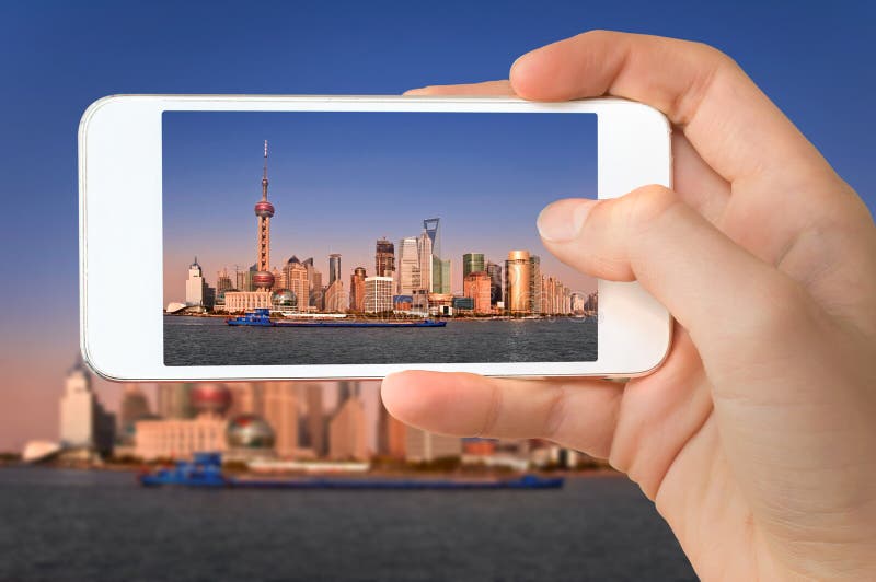 Primo piano di una mano con lo smartphone che prende un'immagine dell'orizzonte di Shanghai e del fiume Huangpu Cina fotografia stock libera da diritti Primo piano di una mano con lo smartphone che prende un'immagine dell'orizzonte di Shanghai e del fiume Huangpu Cina fotografia stock libera da diritti