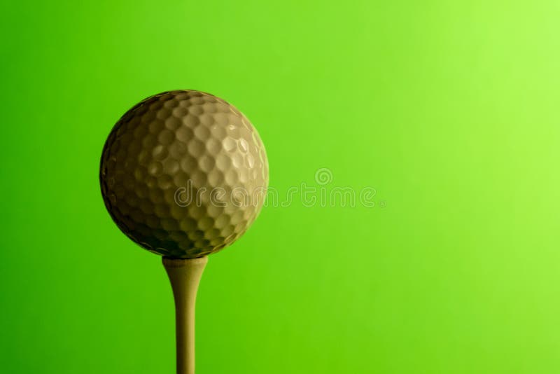 Primo piano il lato ombreggiato di una palla da golf su un T Copi lo spazio Fondo verde intenso dell'insalata fotografia stock Primo piano il lato ombreggiato di una palla da golf su un T Copi lo spazio Fondo verde intenso dell'insalata fotografia stock