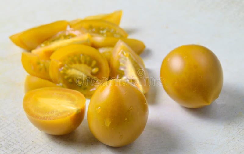 Primo piano rosso affettato dei pomodori ciliegia su un bordo bianco della cucina fotografia stock Primo piano rosso affettato dei pomodori ciliegia su un bordo bianco della cucina fotografia stock