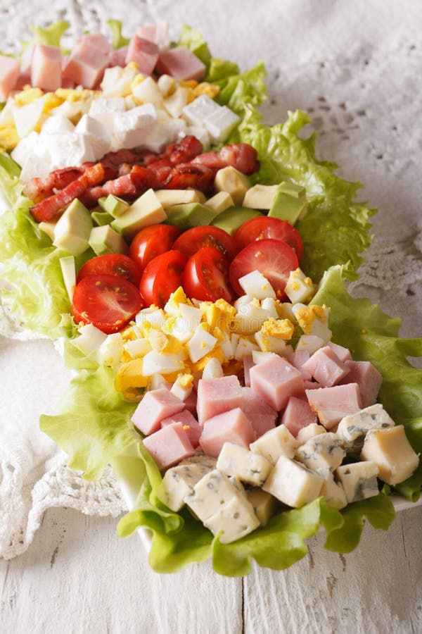 Primo piano saporito dell'insalata di Cobb dell'americano su un piatto verticale fotografia stock libera da diritti Primo piano saporito dell'insalata di Cobb dell'americano su un piatto verticale fotografia stock libera da diritti