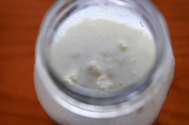Primo piano sparato di un barattolo di vetro riempito di kefir di fermentazione fotografia stock libera da diritti Primo piano sparato di un barattolo di vetro riempito di kefir di fermentazione fotografia stock libera da diritti