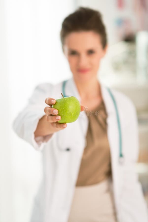 Primo piano su doctor femminile che dà mela verde fotografie stock Primo piano su doctor femminile che dà mela verde fotografie stock