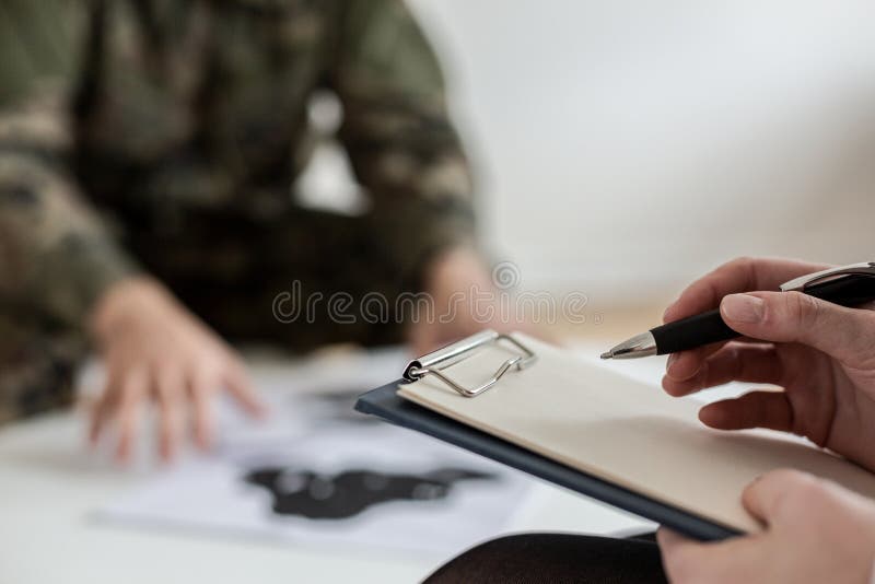 Primo piano sullo psicoterapeuta che prende le note mentre analizzando comportamento del soldato nel corso della riunione