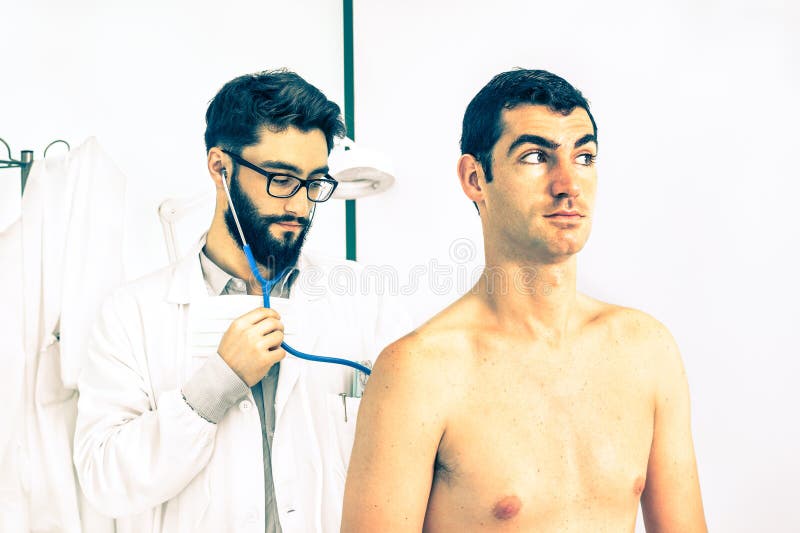Primärdoktor des jungen Hippies an auscultating männlichem Patienten der Arbeit stockbilder Primärdoktor des jungen Hippies an auscultating männlichem Patienten der Arbeit stockbilder