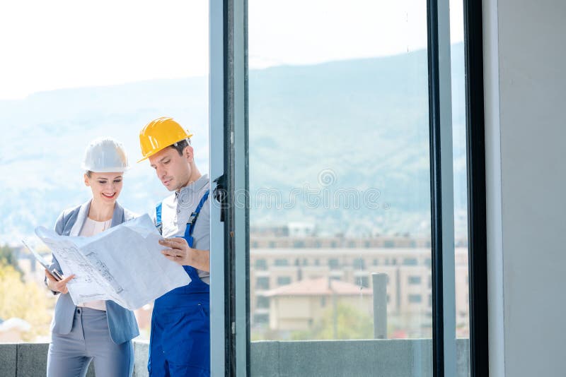 Principal and builder reading blueprints on construction site royalty free stock images