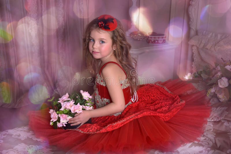 Principessa della bambina in un vestito rosso ed in un cappello si siede sul sofà w immagini stock Principessa della bambina in un vestito rosso ed in un cappello si siede sul sofà w immagini stock
