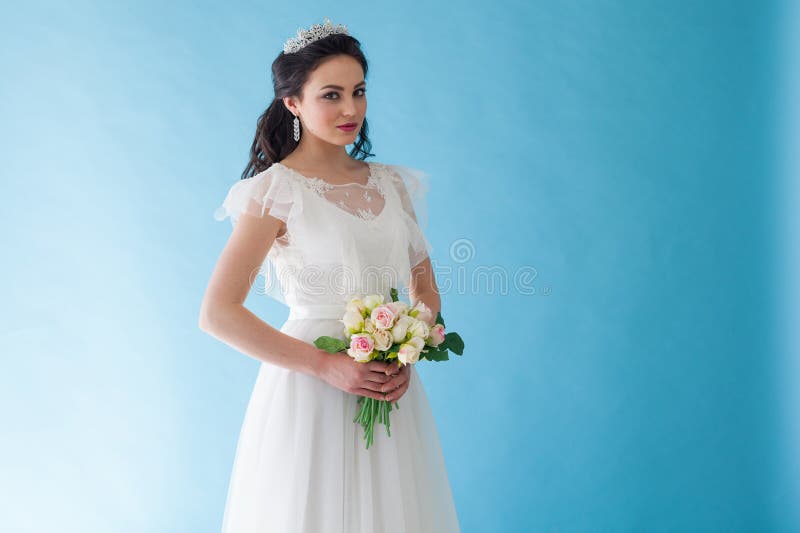 Prinsessa Bride i en vit klänning med en krona på en blå bakgrund royaltyfri bild Prinsessa Bride i en vit klänning med en krona på en blå bakgrund royaltyfri bild