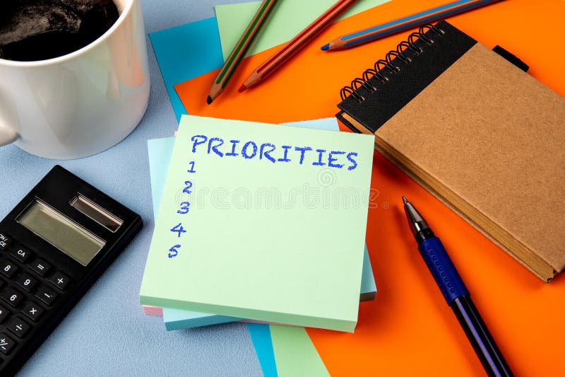 Priorities List. Notepad with text, coffee mug and calculator and stationery on office table stock image