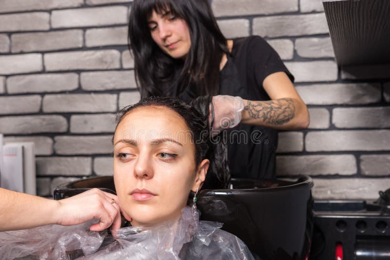 Prise de deux stylistes d'une chemise sur la femme après s'être lavé les cheveux dedans image stock Prise de deux stylistes d'une chemise sur la femme après s'être lavé les cheveux dedans image stock