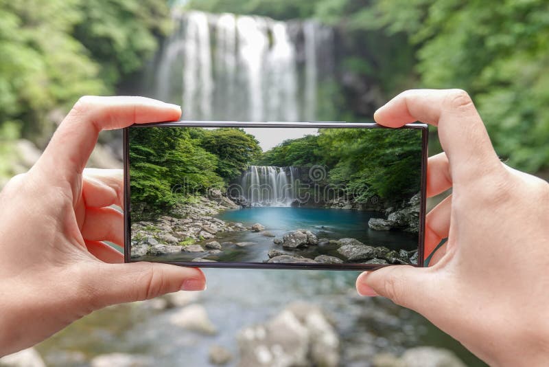 Prise de la photo de la cascade de Cheonjeyeon sur l'île de Jeju, la Corée du Sud avec le téléphone portable Tourisme actif en As photo stock Prise de la photo de la cascade de Cheonjeyeon sur l'île de Jeju, la Corée du Sud avec le téléphone portable Tourisme actif en As photo stock