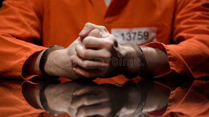 Prisioneiro nos punhos de aperto das algemas, negando a edredão, sala da interrogação