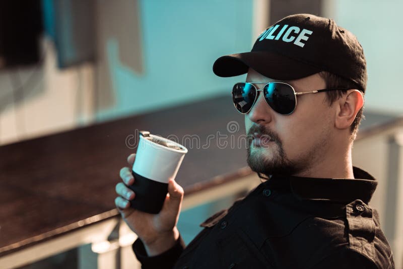 Side View of Smiling Prison Guard Sitting with Cup of Coffee and