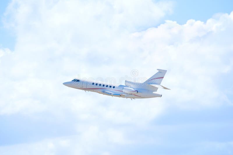 Private business jet airliner plane in flight against fluffy clouds
