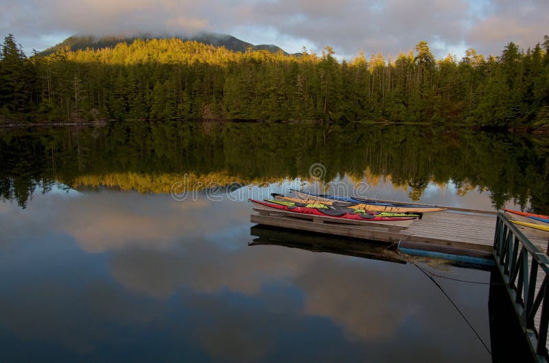 Kayaks on private dock with perfect reflection of mountain and fog in evening light