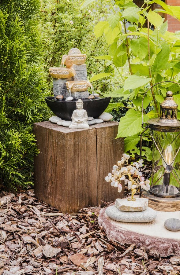 Privater Brunnen des kleinen Hausgartens mit meditierender Buddha-Statue zwischen Bäumen und Büschen. lizenzfreie stockfotos