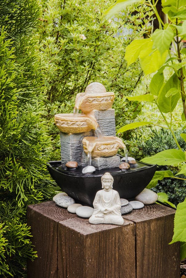 Privater Brunnen des kleinen Hausgartens mit meditierender Buddha-Statue zwischen Bäumen und Büschen. lizenzfreie stockbilder