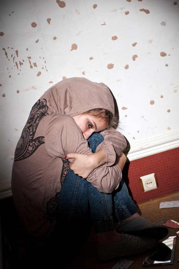 Teenage problems. lonely, unhappy, sad girl sitting on the floor in a dark, dirty room. Teenage problems. lonely, unhappy, sad girl sitting on the floor in a dark, dirty room.