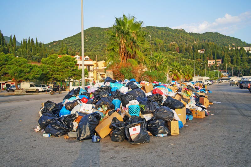 Problemas com acumulação do lixo nas ruas devido às operações de descarga fechadas em Benitses, uma aldeia piscatória em Corfu imagem de stock Problemas com acumulação do lixo nas ruas devido às operações de descarga fechadas em Benitses, uma aldeia piscatória em Corfu imagem de stock
