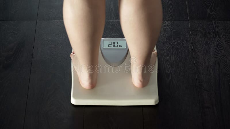 Problème supplémentaire de poids, position femelle de poids excessif sur des échelles, obésité, vue arrière image stock Problème supplémentaire de poids, position femelle de poids excessif sur des échelles, obésité, vue arrière image stock