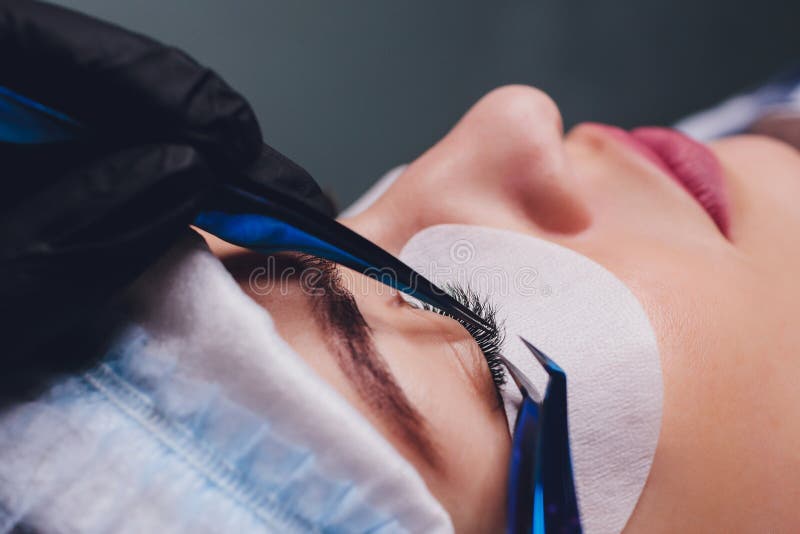 Procedura Di Estensione Di Eyelash Vista ravvicinata dell'occhio femminile con palpebre lunghe Stylist con pinzette rosa, tonalit immagini stock Procedura Di Estensione Di Eyelash Vista ravvicinata dell'occhio femminile con palpebre lunghe Stylist con pinzette rosa, tonalit immagini stock
