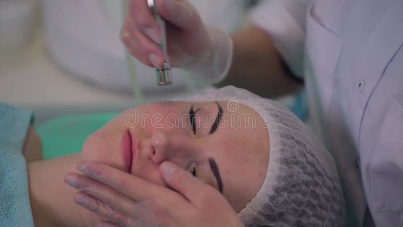 Procedura kosmetologiczna mikrodermabrazja dla dziewczyny z wadliwą skórą. kosmetyk przeprowadza procedurę leczenia zbiory