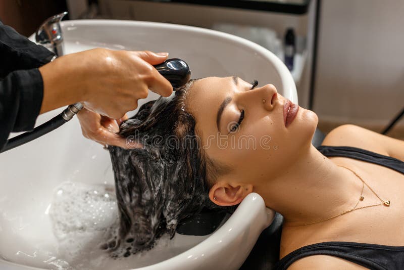 Procedura Mujer joven hermosa con la cabeza que se lava del peluquero en el salón de pelo fotografía de archivo libre de regalías Procedura Mujer joven hermosa con la cabeza que se lava del peluquero en el salón de pelo fotografía de archivo libre de regalías
