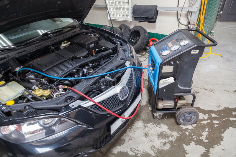 procedure for refueling a car air conditioner using a special device with a blue compressor and a red hose near the open hood