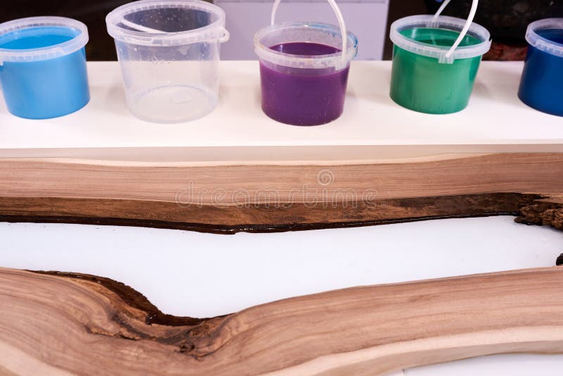 Process making of a craft resin and wood table. Liquid epoxy is poured into a mold with wooden blanks. closeup. Process making of a craft resin and wood table. Liquid epoxy is poured into a mold with wooden blanks. closeup