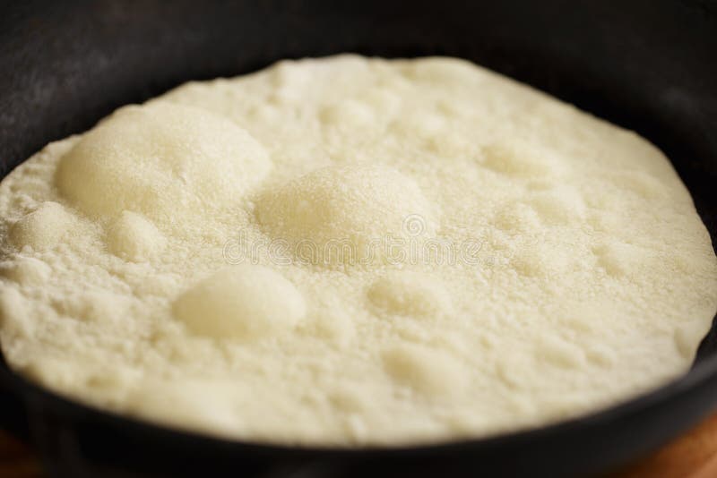 Proces van tortilla ` s het koken op gietijzerpan Bellen die zich op de deeg` s oppervlakte tijdens het braden vormen royalty-vrije stock fotografie Proces van tortilla ` s het koken op gietijzerpan Bellen die zich op de deeg` s oppervlakte tijdens het braden vormen royalty-vrije stock fotografie
