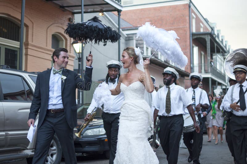 NEW ORLEANS, USA - OCTOBER 10, 2014: Newly wed bride and groom parade through the streets of the French Quarter in New Orleans followed by a jazz band in celebration of their union. NEW ORLEANS, USA - OCTOBER 10, 2014: Newly wed bride and groom parade through the streets of the French Quarter in New Orleans followed by a jazz band in celebration of their union.