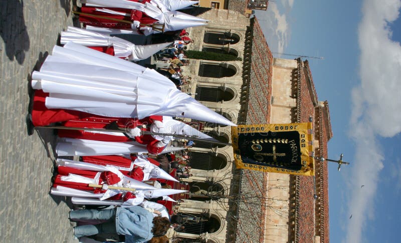 Seville arguably holds the most elaborate processions for Holy Week anywhere in the world. A tradition that dates from medieval times is notable for featuring the procession of pasos, lifelike wood sculptures of individual scenes of the events that happened between Jesus' arrest and his burial, or images of the Virgin Mary showing grief for the torture and killing of her son. These pasos are physically carried in the shoulders of costaleros (literally sack men, usually bodybuilder types who are used to carrying extreme weights). The pasos are set up and maintained by hermandades and cofradÃ­as, religious brotherhoods, confraternities or sodalities, whose precede the paso dressed in Roman military costumes or penitential robes. Those members who wish to do so wear these penitential robes with conical hats, or capirotes, used to conceal the face of the wearer. The robes were widely used in the medieval period for penitents, who could demonstrate their penance while still masking their identity. (These robes intentionally served as the basis for the traditional uniform for members of the Ku Klux Klan in the United States, ironically a very anti-Catholic organisation.) These Nazarenos carry processional candles or wooden crosses, may walk the city streets barefoot, and may carry shackles and chains in their feet as penance. A brass band may accompany the group, playing funereal religious hymns or marchas written for the occasion. Seville arguably holds the most elaborate processions for Holy Week anywhere in the world. A tradition that dates from medieval times is notable for featuring the procession of pasos, lifelike wood sculptures of individual scenes of the events that happened between Jesus' arrest and his burial, or images of the Virgin Mary showing grief for the torture and killing of her son. These pasos are physically carried in the shoulders of costaleros (literally sack men, usually bodybuilder types who are used to carrying extreme weights). The pasos are set up and maintained by hermandades and cofradÃ­as, religious brotherhoods, confraternities or sodalities, whose precede the paso dressed in Roman military costumes or penitential robes. Those members who wish to do so wear these penitential robes with conical hats, or capirotes, used to conceal the face of the wearer. The robes were widely used in the medieval period for penitents, who could demonstrate their penance while still masking their identity. (These robes intentionally served as the basis for the traditional uniform for members of the Ku Klux Klan in the United States, ironically a very anti-Catholic organisation.) These Nazarenos carry processional candles or wooden crosses, may walk the city streets barefoot, and may carry shackles and chains in their feet as penance. A brass band may accompany the group, playing funereal religious hymns or marchas written for the occasion.