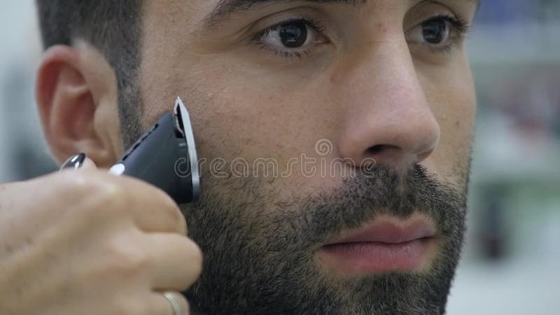 Proceso del Hairstyling Primer de un cabello seco del peluquero de un hombre barbudo joven