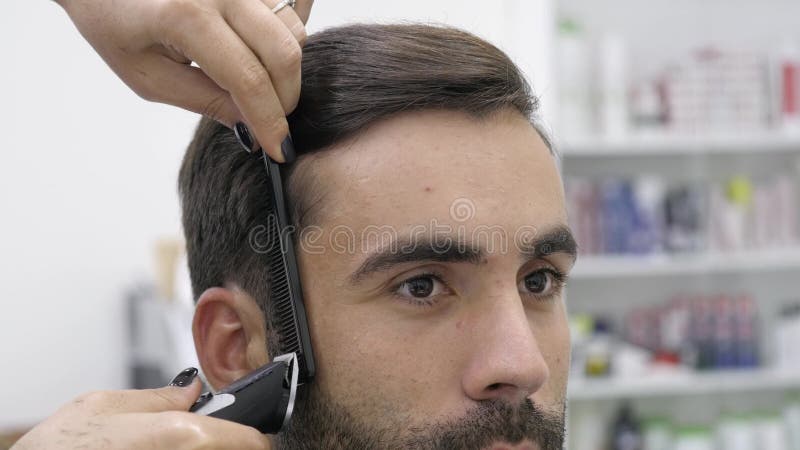 Proceso del Hairstyling Primer de un cabello seco del peluquero de un hombre barbudo joven