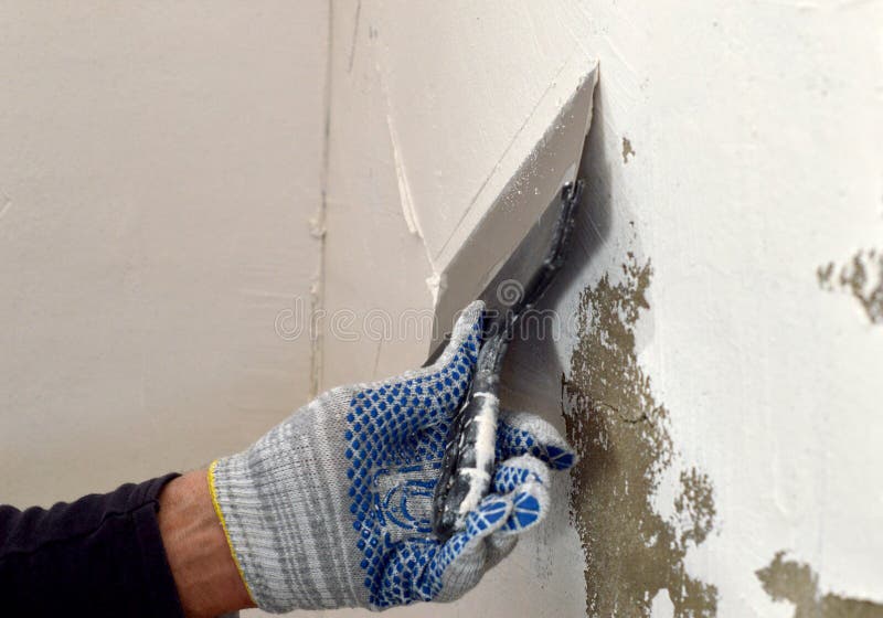The Process of Applying a White Putty on Concrete Gray Wall Stock Photo
