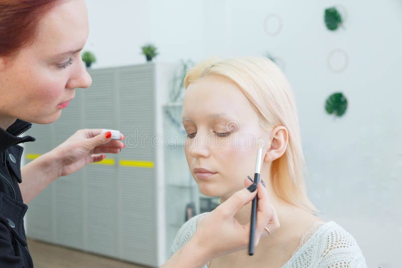 Process av danandemakeup Sminkkonstn?r som arbetar med borsten p? modellframsida royaltyfria bilder Process av danandemakeup Sminkkonstn?r som arbetar med borsten p? modellframsida royaltyfria bilder