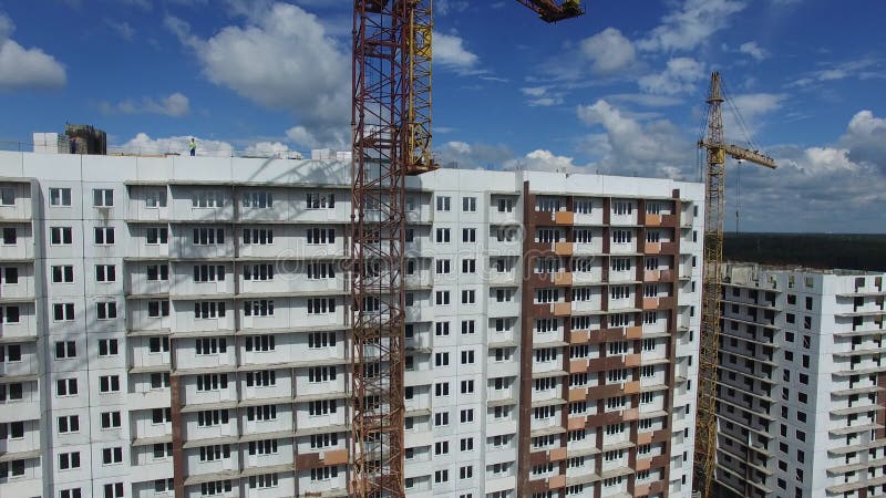 Construction workers building an apartment building in a field, aerial view