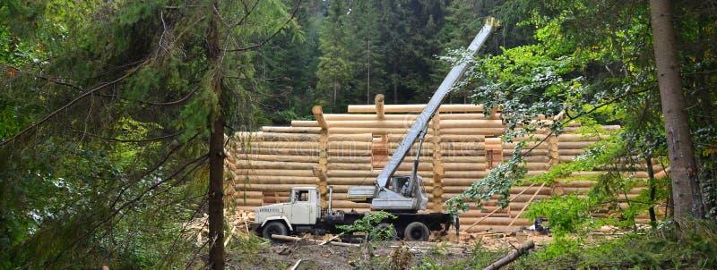 The process of building a wooden house from wooden beams of cylindrical shape. Crane in working condition royalty free stock image The process of building a wooden house from wooden beams of cylindrical shape. Crane in working condition royalty free stock image