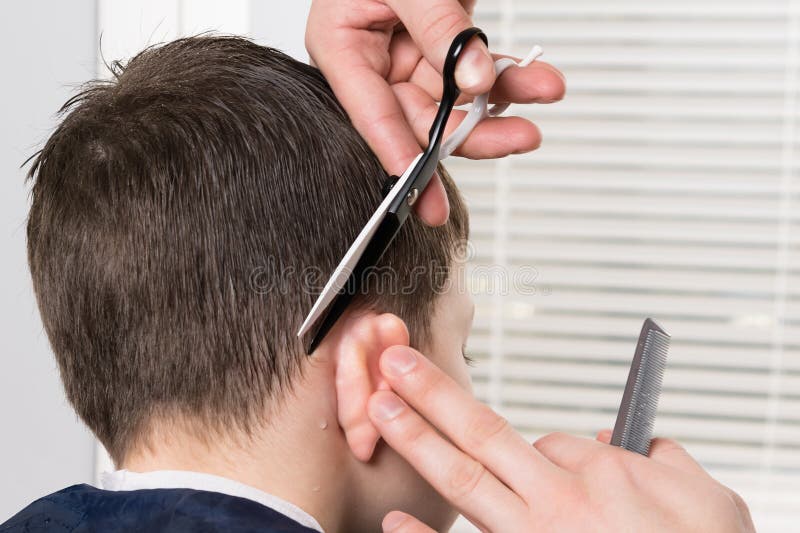 The Process of Child Hair Cutting Behind the Ear with Scissors