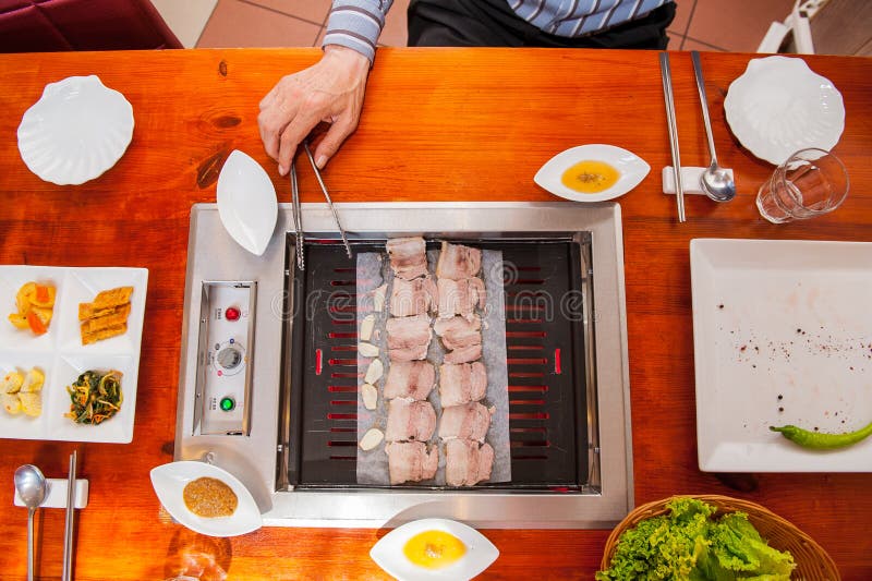 Process of Cooking Korean Barbecue Raw Pork on the Tabletop Grill in