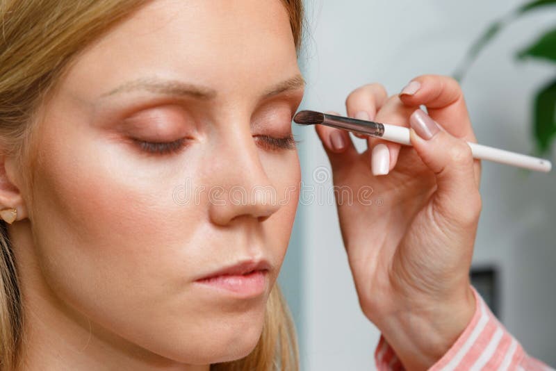 The Process of Creating Makeup. Makeup Artist Working with a Brush on