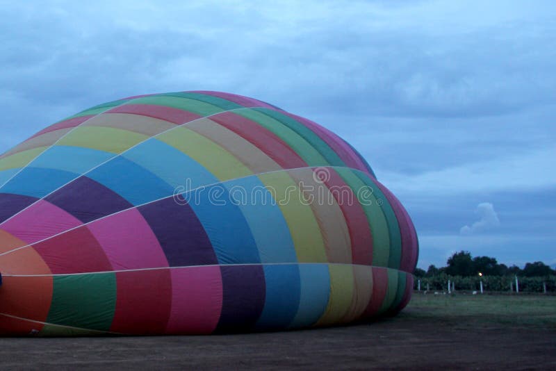 Process of Inflation and Preparation of Hot Air Balloon at Sunrise for Flight in Cloudy Sky