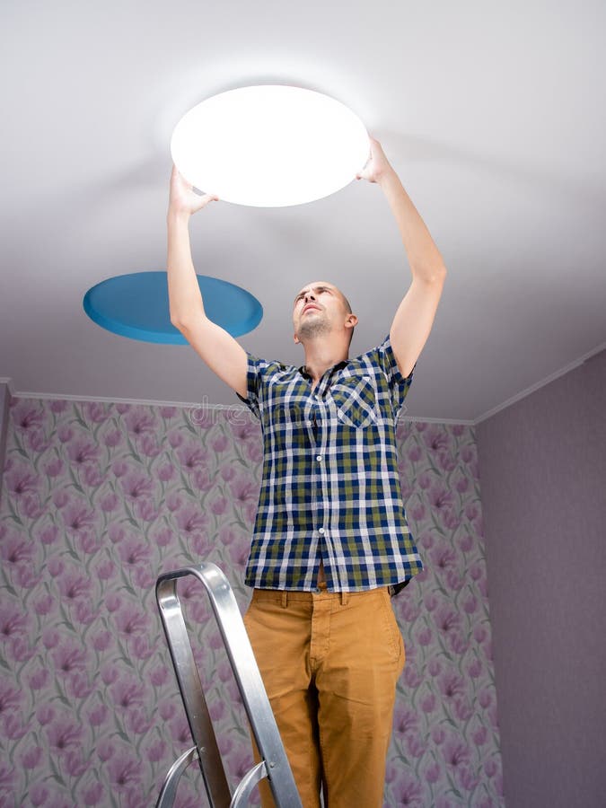 A Man Installs a Modern Led Ceiling Light on the Ceiling. Stock Image