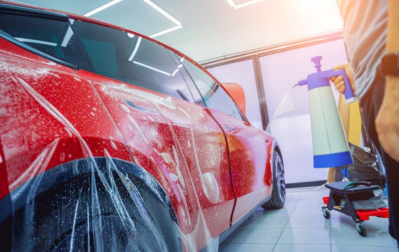 The Process of Installing Protective Film on the New Red Car. Stock